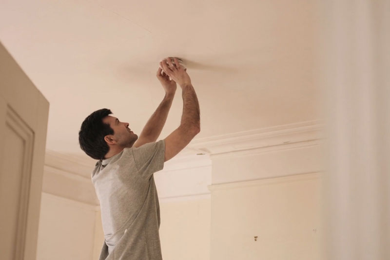 man replacing CO detector batteries.